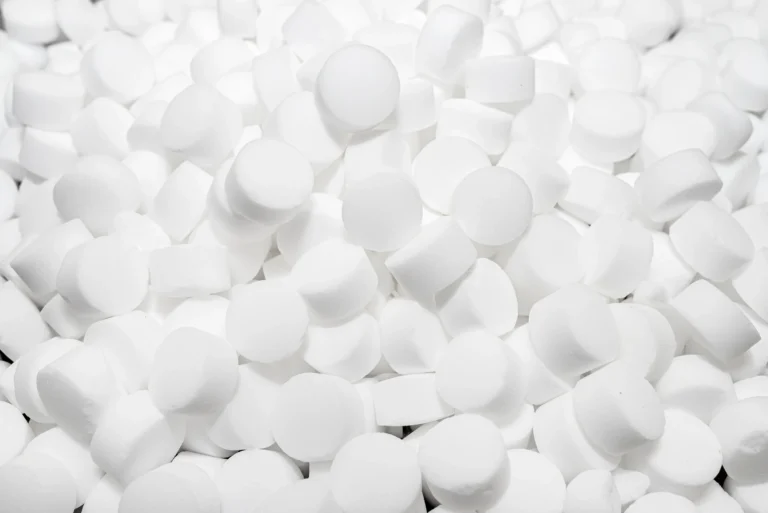 A large pile of small, round, white tablets closely packed together.